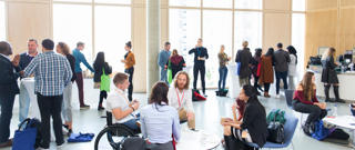 Wide angle view of leaders at a networking event, some are sitting and some are standing.